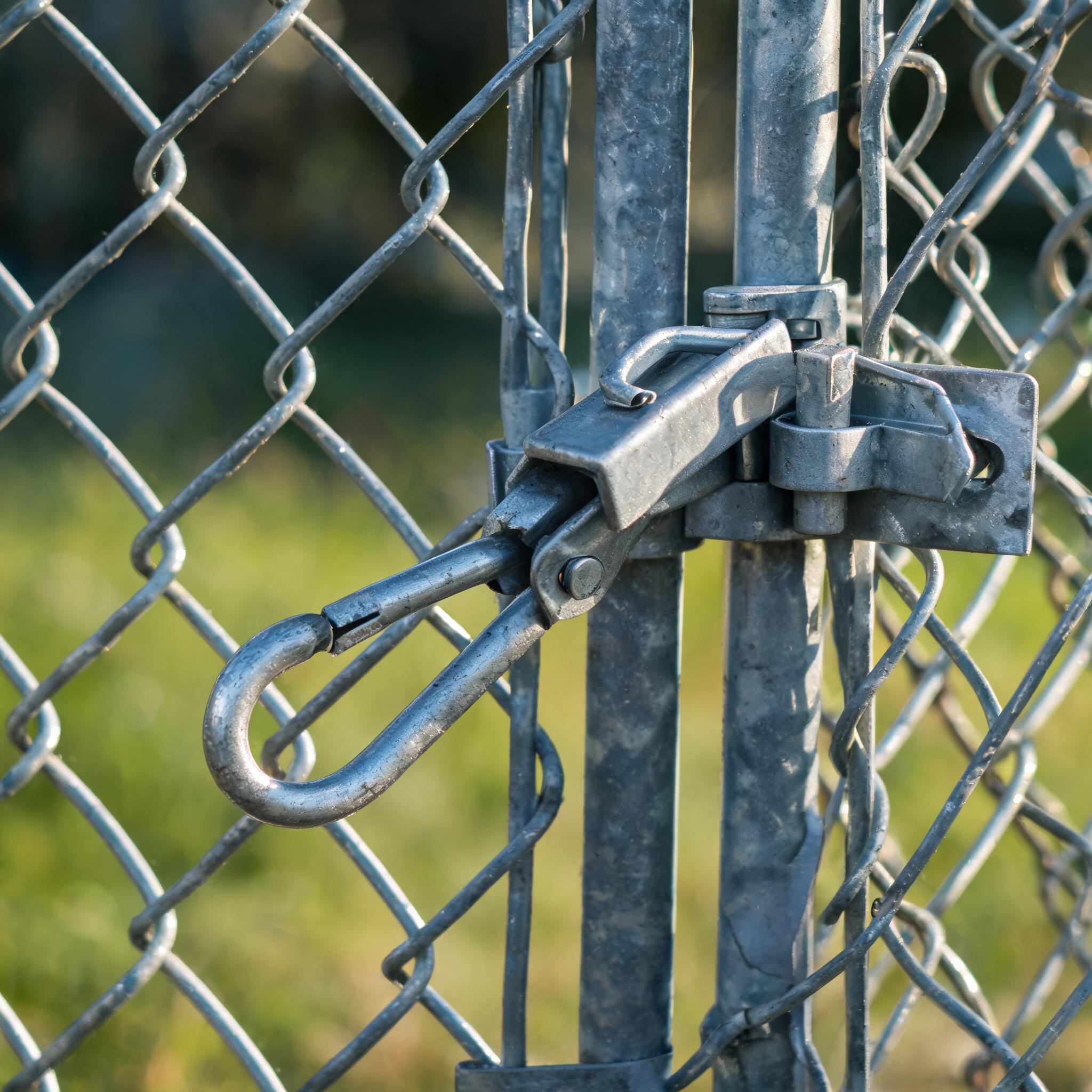 Close-up of an open metal gate latch on a chain-link fence with sunlight on the links
